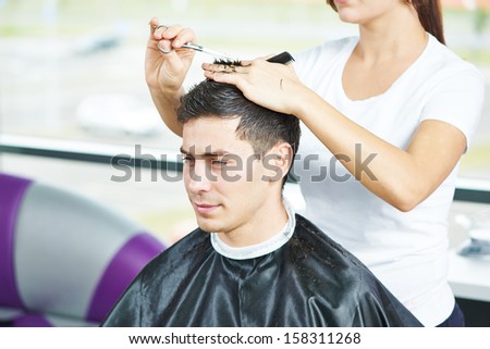 Female hairdresser cutting hair of smiling man client at beauty parlour Royalty-Free Stock Photo #158311268