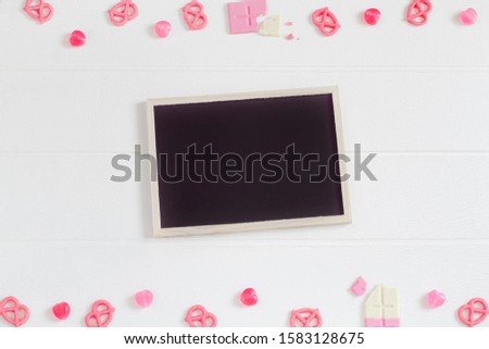 Valentine's frame composition background, pink chocolate, candy, black chalkboard on white wooden table texture, copy space for card or sale promotion for online business banner design, flat lay