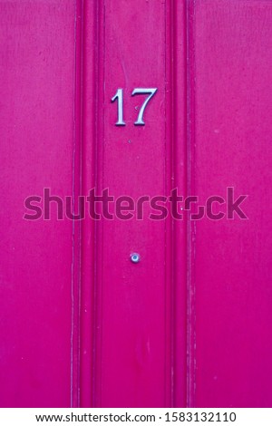 House number 17 on a fuchsia wooden front door