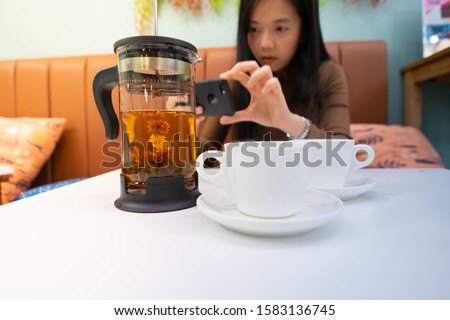A woman Take a picture of tea from a mobile phone