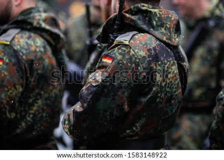 Details with the uniform and the flag on it of a German soldier taking part at the Romanian National Day military parade. Royalty-Free Stock Photo #1583148922