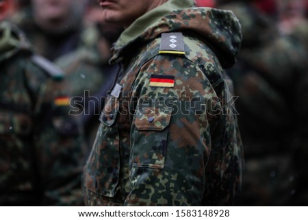 Details with the uniform and the flag on it of a German soldier taking part at the Romanian National Day military parade. Royalty-Free Stock Photo #1583148928