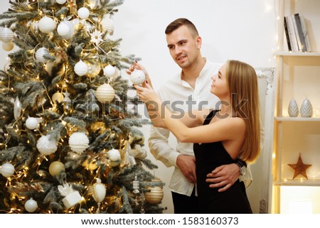 beautiful, in love couple dress up Christmas tree. the guy hugs the girl, look into her eyes. love