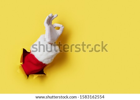 Santa Claus hand showing OK isolated on yellow background