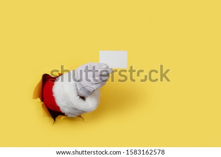 Santa Claus Holding a Blank White Card isolated over yellow. Shopping, Sales, Giving Gift for Black Friday, Christmas and New Year 2020 concepts.