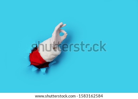Santa Claus hand showing OK isolated on light blue background