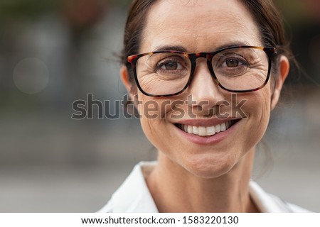 Portrait of mature businesswoman wearing eyeglasses and looking at camera. Close up face of cheerful woman with spectacles smiling outdoor. Confident beautiful entrepreneur wearing specs. Royalty-Free Stock Photo #1583220130