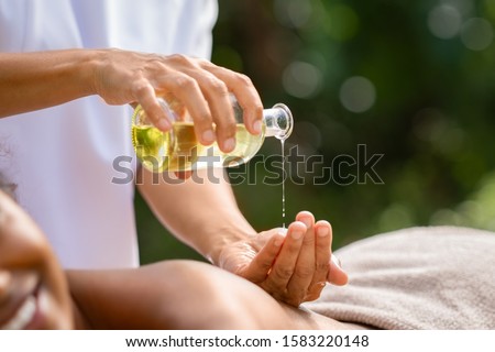 Closeup of masseuse hands pouring aroma oil on woman back. Woman prepare to do oriental spa massage for relaxing treatment. Therapist doing aromatherapy oil massage on girl body. Body care concept. Royalty-Free Stock Photo #1583220148