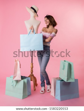 Asian pretty young woman walking over pink  pastel background. She smiling and  holding shopping bags. she nice-looking lovely attractive shine .