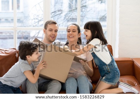 Happy daughter and brother with parent opening gift box. Smiling siblings with mom and dad surprised new soft toy on birthday. Royalty-Free Stock Photo #1583226829