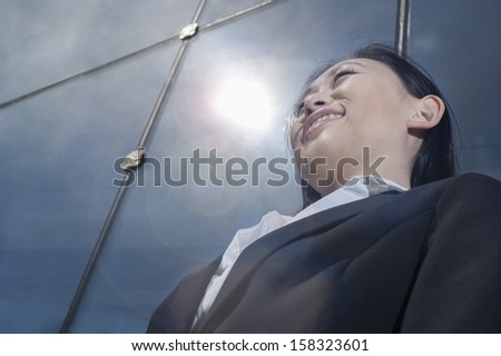 Young smiling businesswoman outside in front of glass building