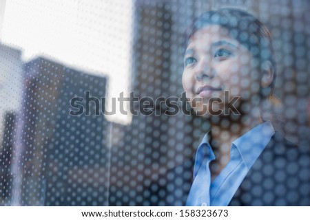 Businesswoman looking out through window, reflection of the city on the glass
