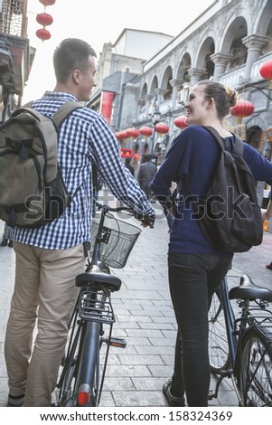 Rear view of young man and woman with bicycles
