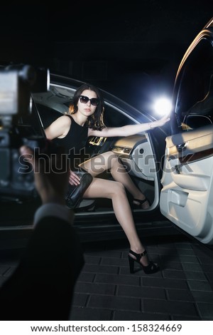 Paparazzi photographer taking photo of young beautiful woman stepping out of car 