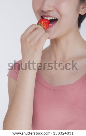 Young woman in pink shirt eating a strawberry