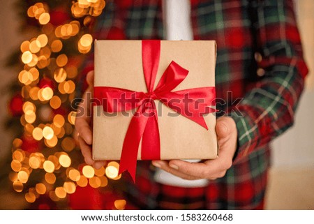 Adult man holds in his hand a box with a gift for Advent holiday.  Happy New Year and Merry Christmas