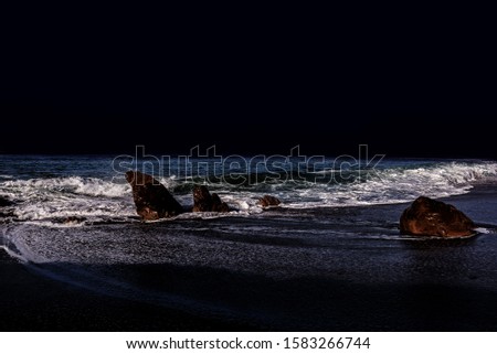 Waves and whitewater breaking on a moonlit beach at twilight
