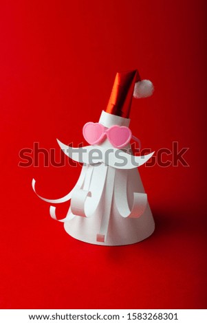 Homemade paper figure of Santa Claus on red background with love (heart form) sun glasses. Christmas art, banner for celebrate.