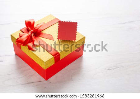 Gift box and red tag on wooden background