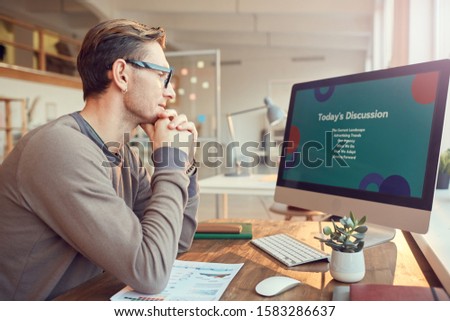 Side view portrait of adult businessman looking at computer screen while preparing for presentation or online conference at desk in office, copy space Royalty-Free Stock Photo #1583286637