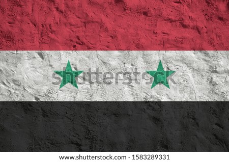 Syria flag depicted in bright paint colors on old relief plastering wall. Textured banner on rough background