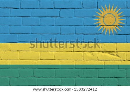 Rwanda flag depicted in paint colors on old brick wall. Textured banner on big brick wall masonry background