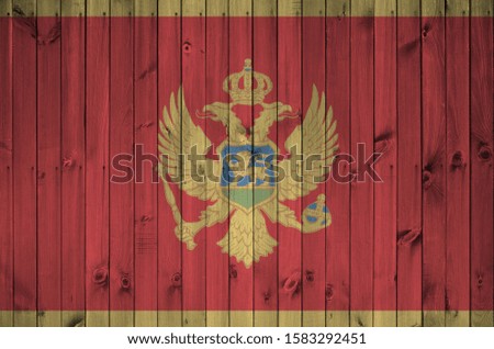 Montenegro flag depicted in bright paint colors on old wooden wall. Textured banner on rough background