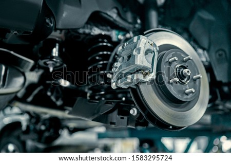 Disc brake of the vehicle for repair, in process of new tire replacement. Car brake repairing in garage.Suspension of car for maintenance brakes and shock absorber systems.Close up. Royalty-Free Stock Photo #1583295724