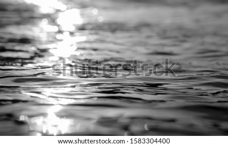Reflection of cold light in water.Black river waves texture.Black and white sea background