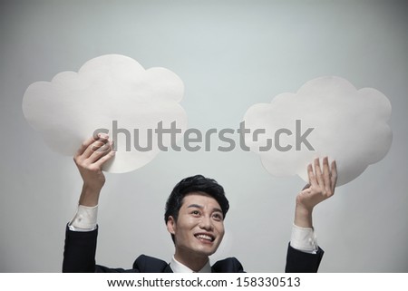 Smiling businessman holding two paper clouds