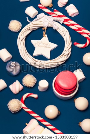 Merry Christmas. Christmas composition with white christmas tree decorations and new year candies on blue background. Marshmallow and cane candies on classic blue background. 