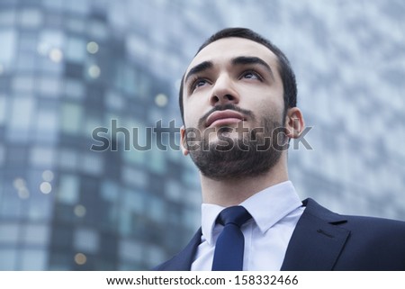 Portrait of serious young businessman looking up