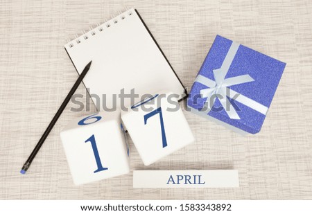 Calendar with trendy blue text and numbers for April 17 and a gift in a box.