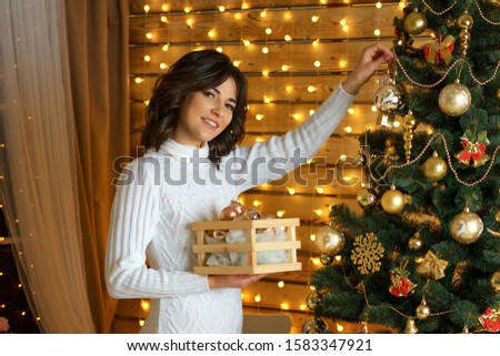 happy woman dresses up a festive Christmas tree, hangs balls