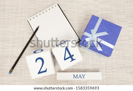 Calendar with trendy blue text and numbers for May 24 and a gift in a box.