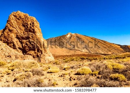 Highest Peak Behind A Large Lava Rock On A Sunny And Very Clear Day In El Teide National Park. April 13, 2019. Santa Cruz De Tenerife Spain Africa. Travel Tourism Street Photography.