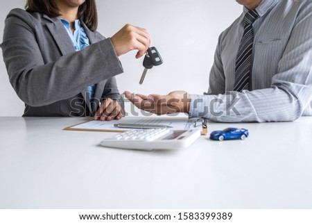 Car rent agent manager holding key of new car giving to businessman client after signing good deal agreement contract, renting considering vehicle.