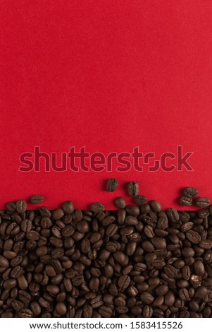Coffee beans are scattered on red paper background close-up, commercial copy space.