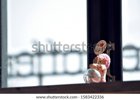 A plate with wording "I love you" and a ball with the doll put in front of a handle of window.