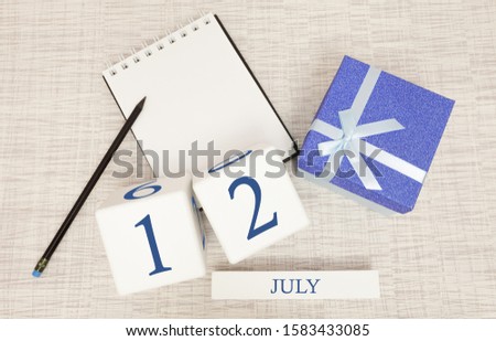 Calendar with trendy blue text and numbers for July 12 and a gift in a box.