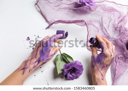 Artist's hands in paint, flowers and cloth on white background