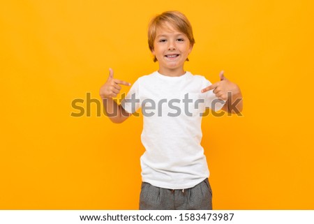 attractive european boy in a white t-shirt with mockup on an orange background with copy space