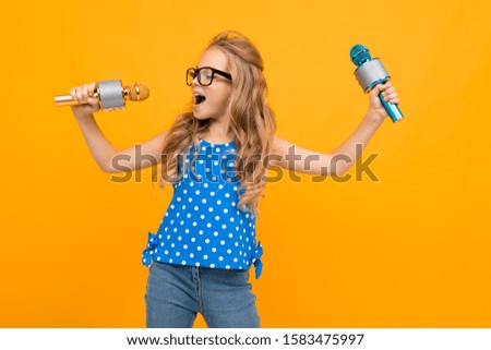 A little girl with glasses with a microphone is interviewed, the picture is isolated on yellow background