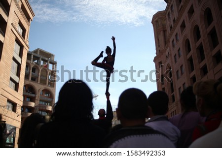 A lot of people gathered together watching a young girl performing a ballet dance  outdoors