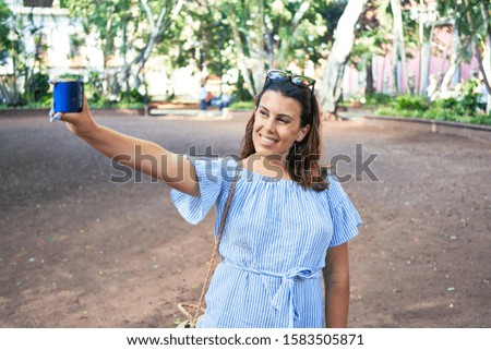 Young beatiful woman smiling happy and cheerful at green park taking a selfie using smartphone on a sunny day of summer