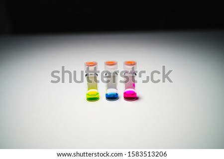 Three colourful liquid in different LCMS glass vial on a white bench with black background for medical research in a chemistry laboratory. Corona Virus and vaccine development. 