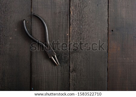 old pliers on black wooden 