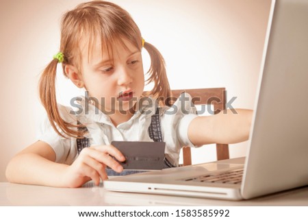 Business child girl working remotely with credit card and using laptop computer. 
