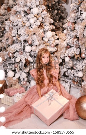 fashion interior photo of beautiful girl with blond hair in elegant dress posing with presents near decorated Christmas tree 