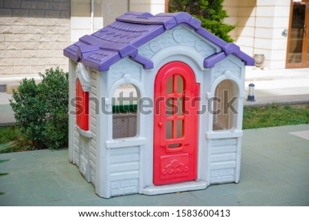 plastic colorful house . Entertainment area.kids playhouse in the entertainment center. Plastic children play house . Green floor. Joy and fun. Playing games.with red door and red window .Game house . Royalty-Free Stock Photo #1583600413